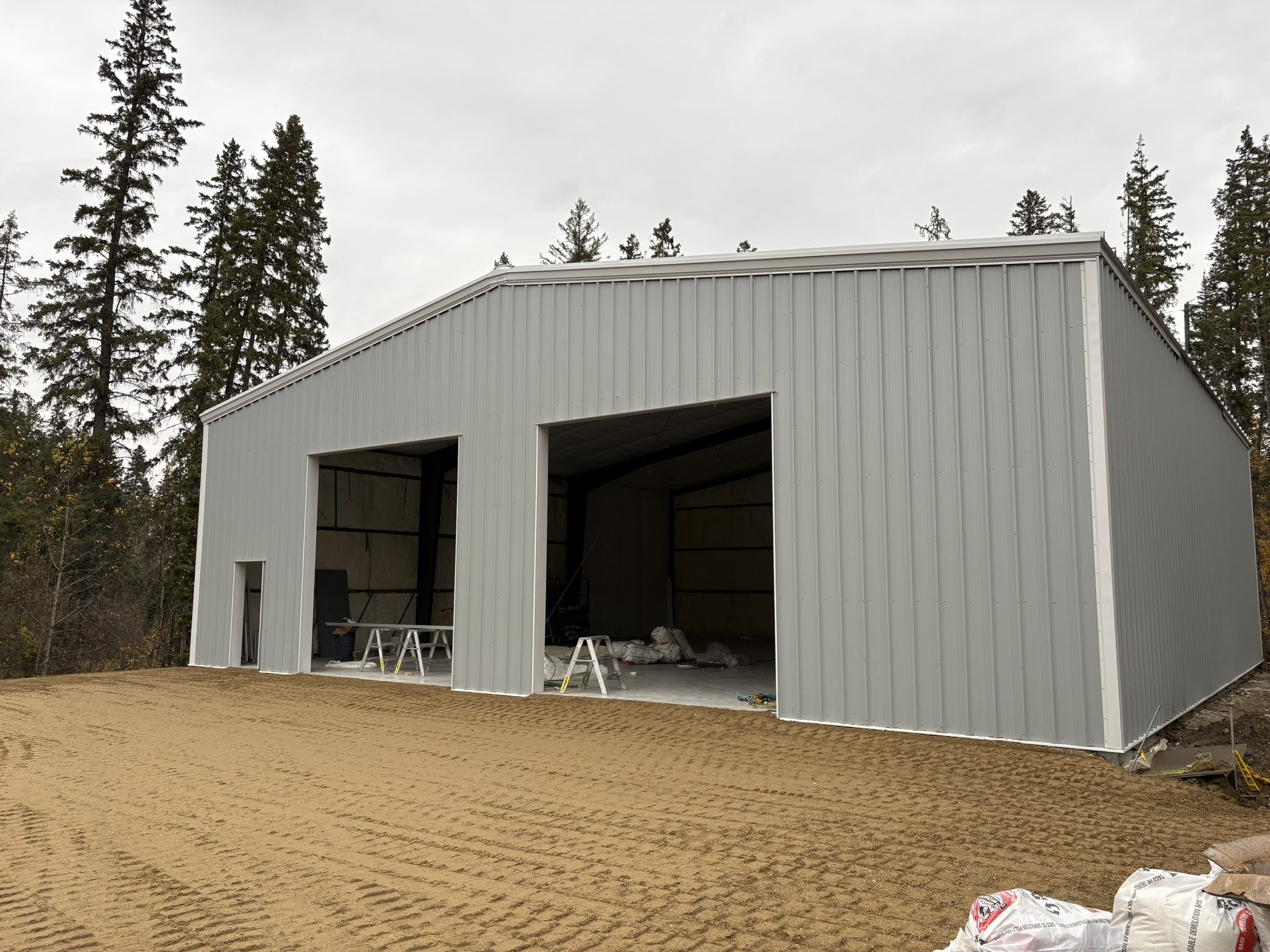 Steel building with light grey cladding and two large door openings during construction