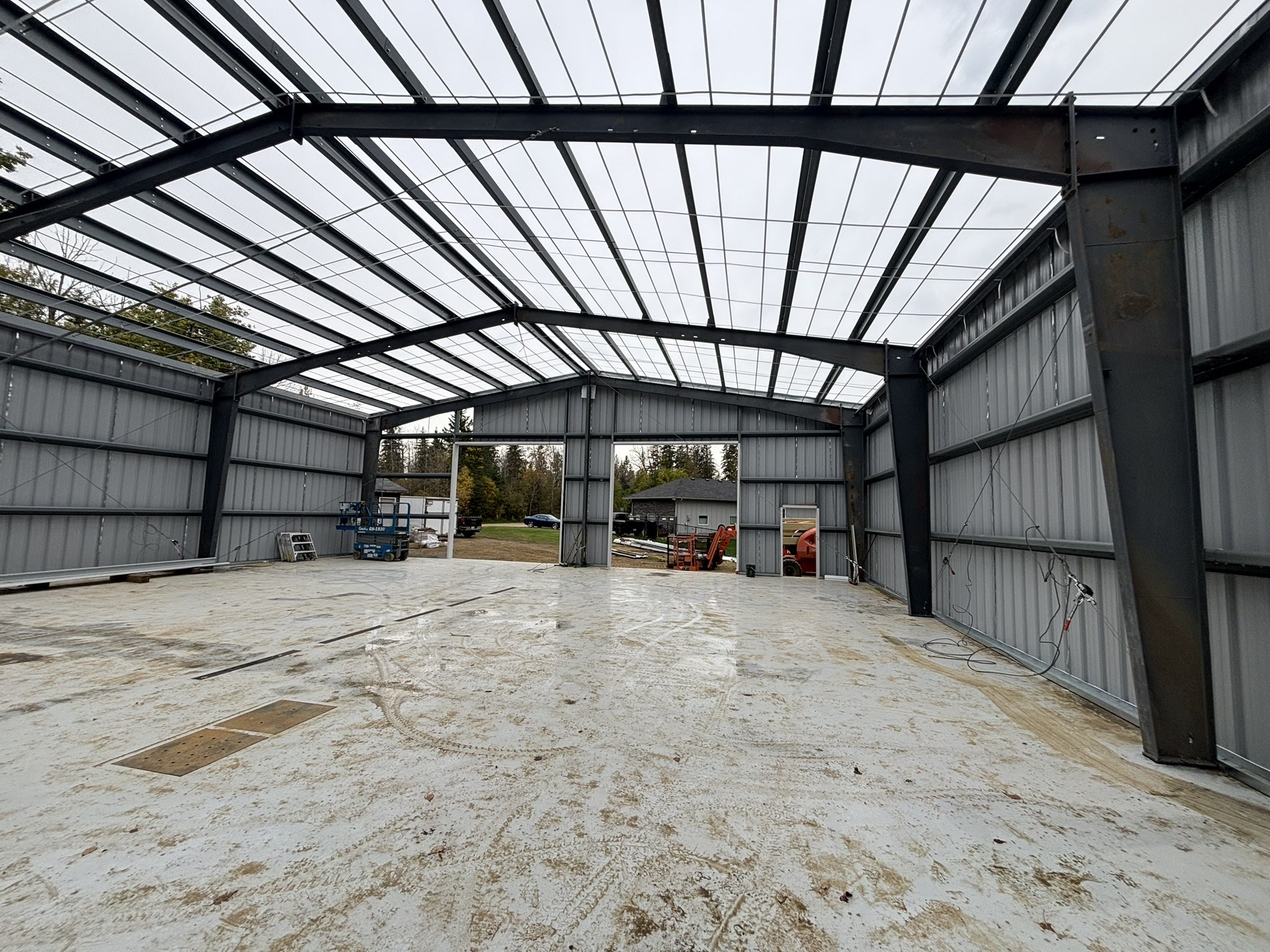 Steel building interior showing roof framing, wall cladding and concrete floor